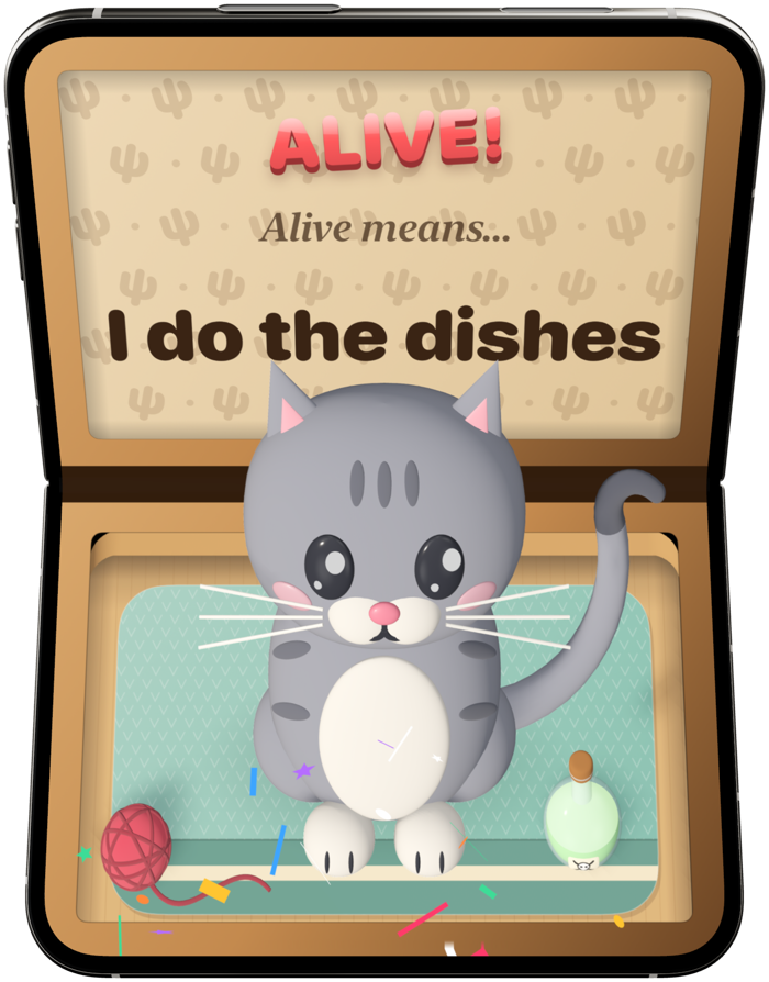 A grey kitten sitting in a cardboard box beside a ball of wool, under ALIVE! and “I do the dishes”